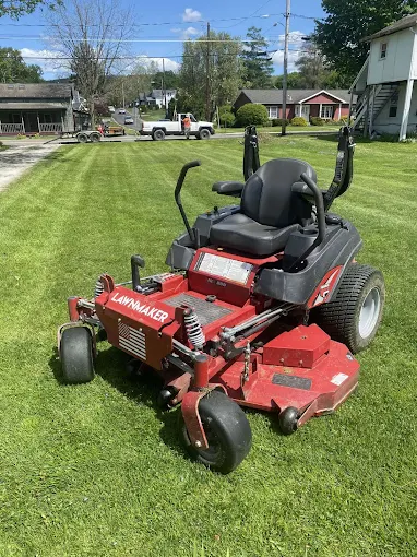Red Lawnmaker zero-turn commercial mower parked on a freshly striped lawn in Vestal, NY.
